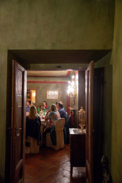 A group of diners gathers around a candlelit table in a rustic Italian restaurant, experiencing the warmth of a small group tour in Italy.