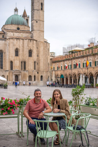 Chantelle and Giovanni, co-founders of The Italian on Tour, locals and Italy experts sitting at a green table in a piazza