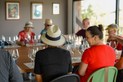 A group of travelers, dressed casually with sun hats, enjoys a wine tasting experience in a charming Italian setting, part of a curated small group tour.