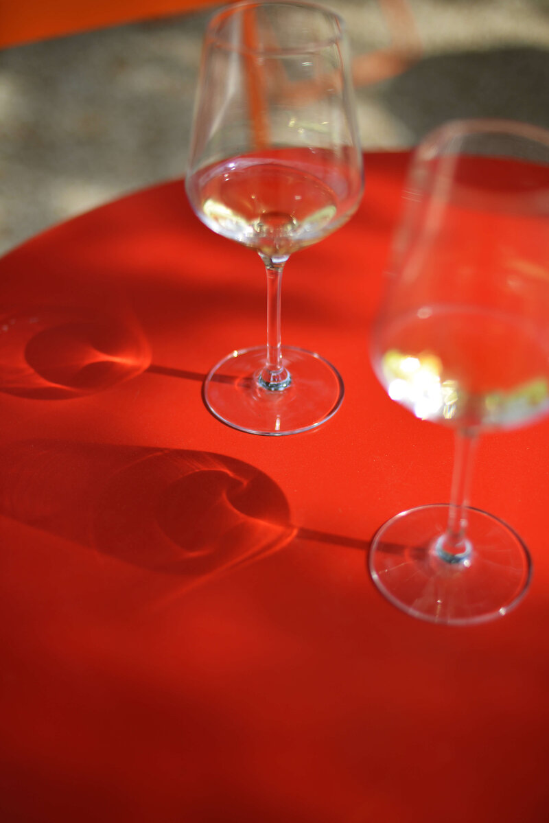 a glass of white wine in an food and wine italy tour sitting on a red table