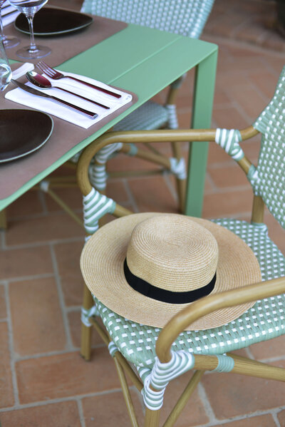 A classic straw hat with a black ribbon sitting on an empty chair