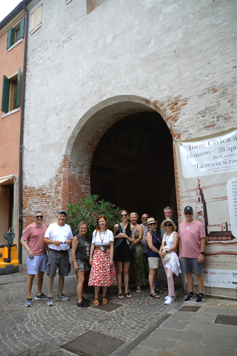 A small group of people pose in front of an old building On the Italian on Tour’s 10 day Northern Italian Delights Food & Wine Tour