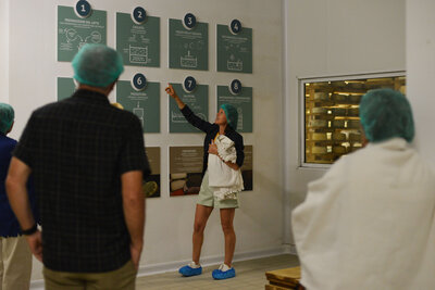 A small group of travelers listens to a guide inside a local Italian factory, learning about traditional craftsmanship and supporting small businesses.
