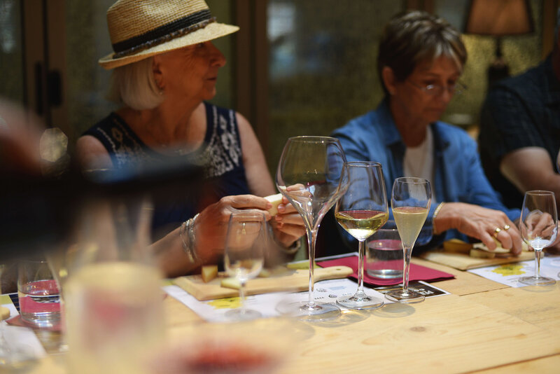 A small group enjoys a food and wine tour in Italy, toasting with glasses of wine over a beautifully set table with gourmet dishes. The intimate setting highlights the experience of an off-the-beaten-path Italy small group tour