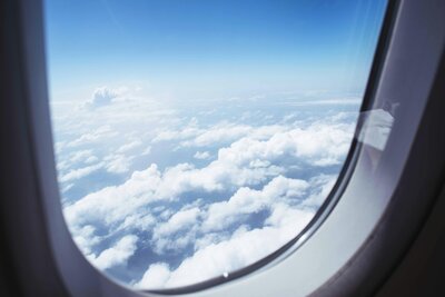 A view from an airplane window showing clouds and sky, representing flight options for traveling to Italy.