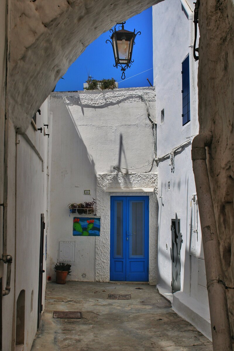 An off the beaten path view of italy with whitewashed walls and blue doors as seen On the Italian on Tour’s 8 day Passport to Puglia Food & Wine Tour