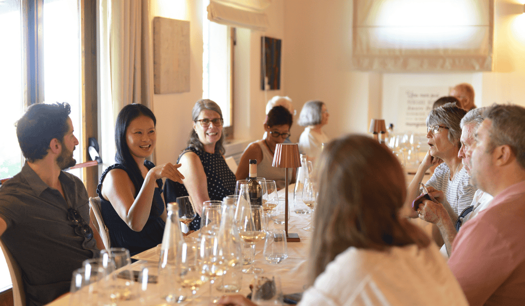 a group of people around the dining table on a small group italy tour enjoying a meal paired with local wines