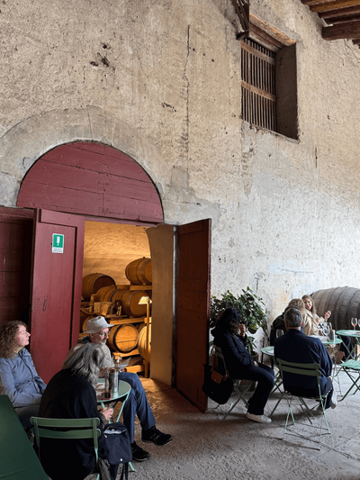 Travelers sit and engage in conversation with locals at a rustic Italian venue, experiencing authentic connections on a small group tour.