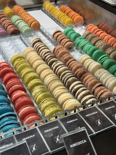 An array of colorful macarons lined up in a display, showcasing one of Italy’s hidden culinary gems beyond the typical tourist spots.