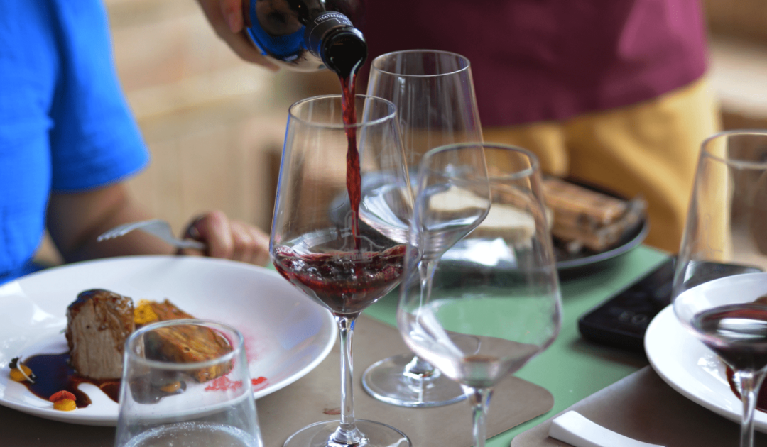table with red wine being poured into wine glass